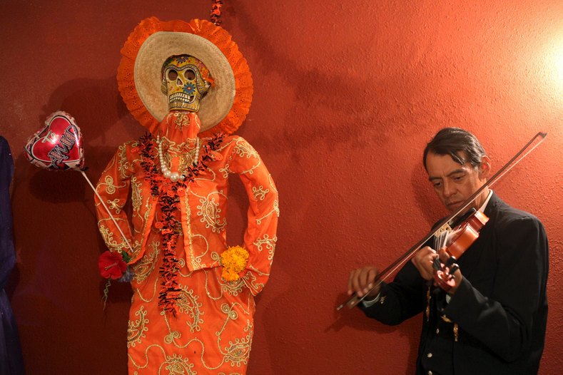 A musician plays his violin next to a depiction of La Santa Muerte (Saint Death) at a shrine during Day of the Dead celebrations in Ciudad Juarez, Mexico.