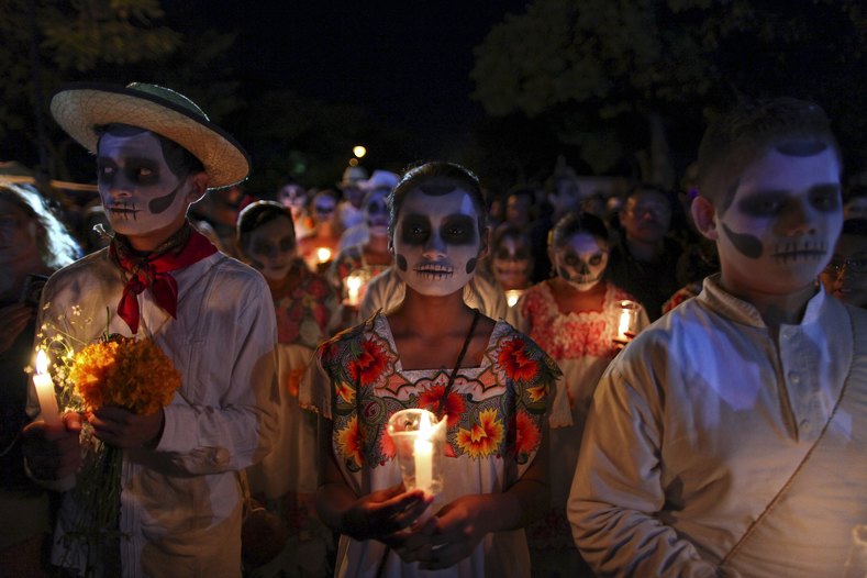 People, with their faces painted as skulls, take part in a traditional parade called 