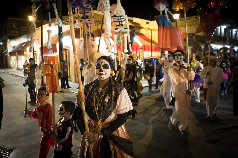 Dozens of men and women in traditional dress parade in Oaxaca, Mexico.