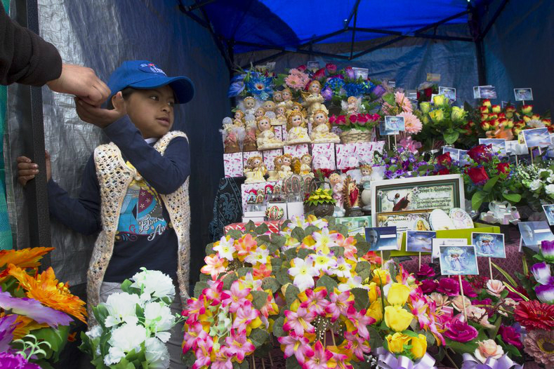 A girl collects payment at a shop outside a cemetery known for its topiary art, during the observance of the Day of the Dead, in Tulcan, Ecuador A girl collects payment at a shop outside a cemetery known for its topiary art, during the observance of the Day of the Dead, in Tulcan, Ecuador.