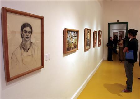 A woman looks at paintings from Mexican artists Frida Kahlo and Diego Rivera during a preview tour of a new exhibition at the Casa Azul Museum in Mexico City July 4, 2007.