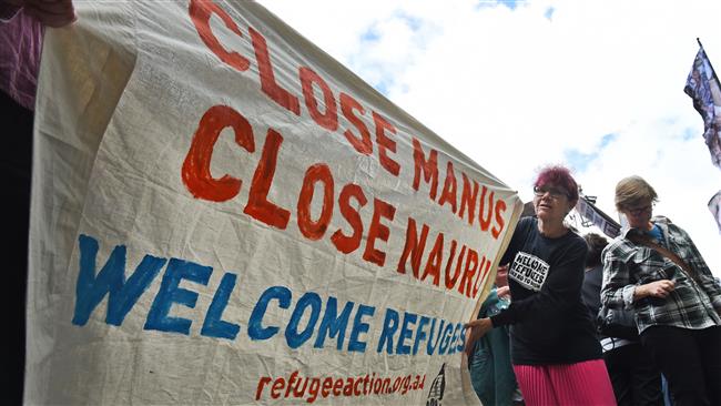 A pro-refugee protester holds up a banner outside the Transfield Services annual general meeting in Sydney on October 28, 2015.