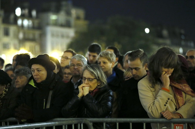 People gather outside Notre Dame Cathedral where a mass is held following a series of deadly attacks in Paris, Nov. 15, 2015.