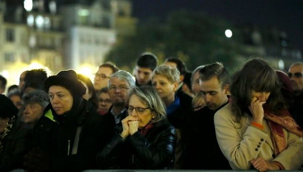 People gather outside Notre Dame Cathedral where a mass is held following a series of deadly attacks in Paris, Nov. 15, 2015.