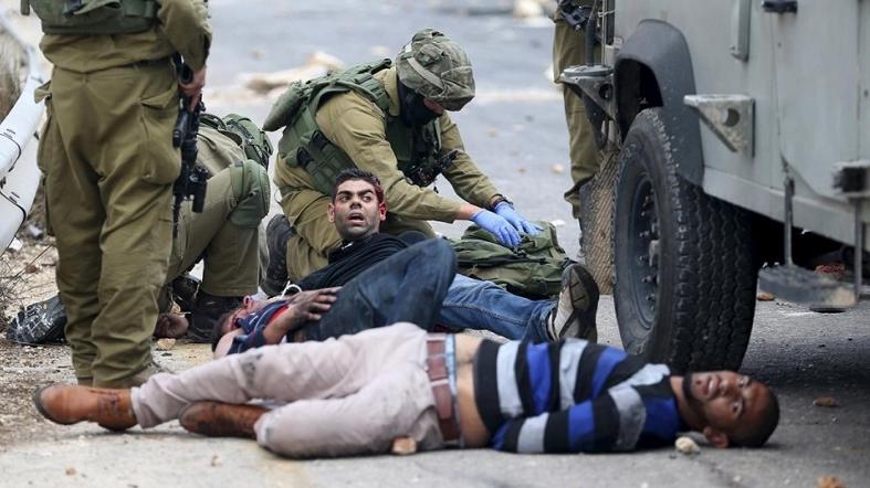 Israeli soldiers detain wounded Palestinian protesters during clashes near the Jewish settlement of Beit El.