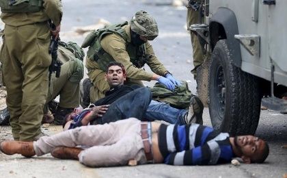 Israeli soldiers detain wounded Palestinian protesters during clashes near the Jewish settlement of Beit El.