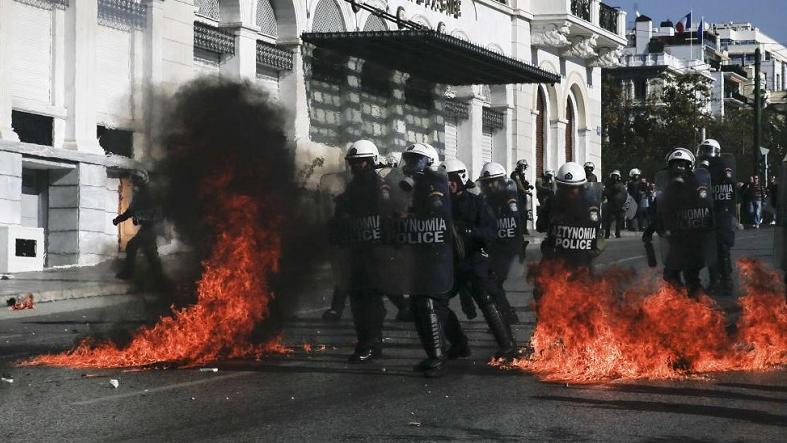 Riot policemen walk by fires caused by petrol bombs thrown by youths following brief clashes between police and protesters during a 24-hour general strike in central Athens, Greece Nov. 12, 2015.