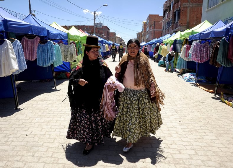 Aymara women walk at the fair.