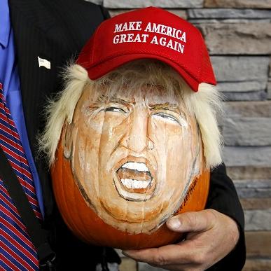 A supporter of U.S. Republican presidential candidate Donald Trump holds a pumpkin painted in the likeness of Trump in Illinois, United States, Nov. 9, 2015.