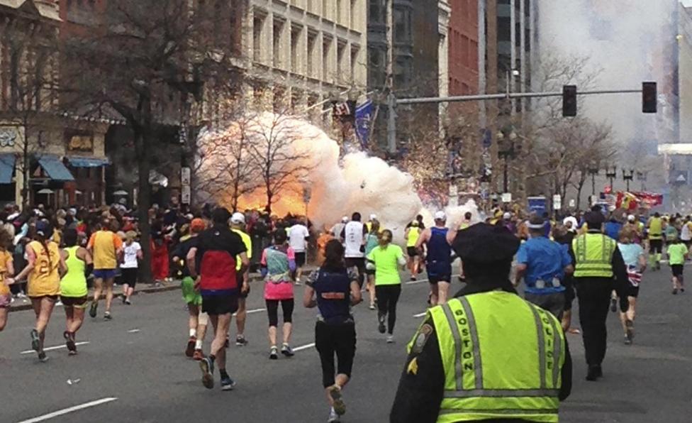 Runners run towards the finish line of the Boston Marathon as an explosion erupts near the finish line of the race in Boston, Massachusetts, April 15, 2013.