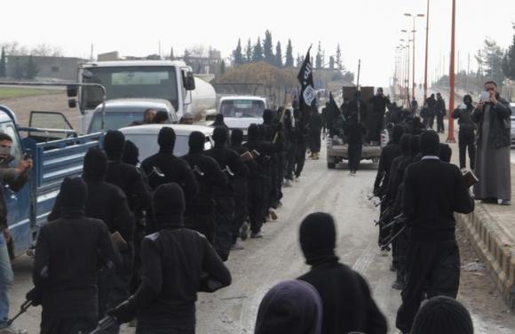 Islamic State group fighters parade at the Syrian town of Tel Abyad, near the border with Turkey, on Jan. 2, 2014.