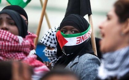 A Bedouin woman, covering her face with a Palestinian flag, marches during a protest in Israel.