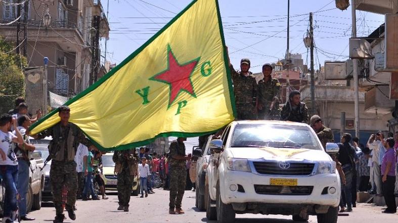 Kurdish People's Protection Units (YPG) fighters wave their flag in northeastern Syrian town of Qamishli.