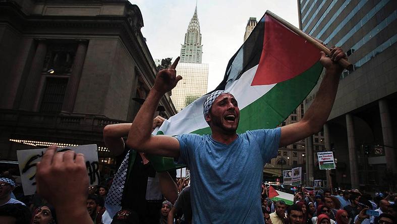 A man waves the Palestinian national flag as he shouts, 
