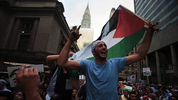 A man waves the Palestinian national flag as he marches with a demonstration.