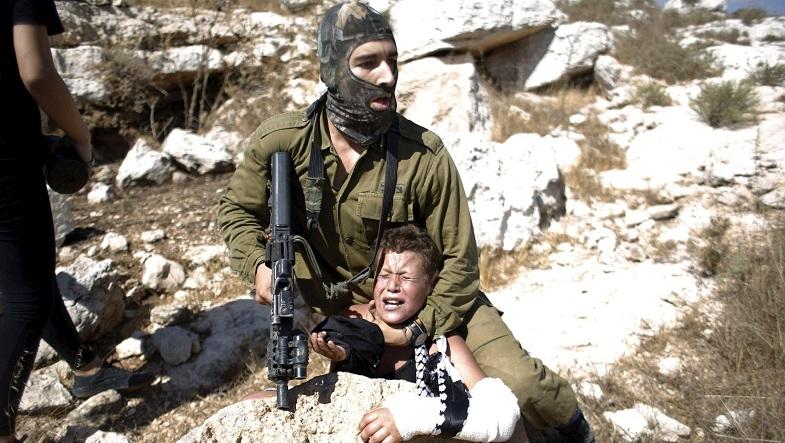 An Israeli soldier detains a Palestinian boy during a protest against Jewish settlements in the West Bank village of Nabi Saleh, near Ramallah August 28, 2015.