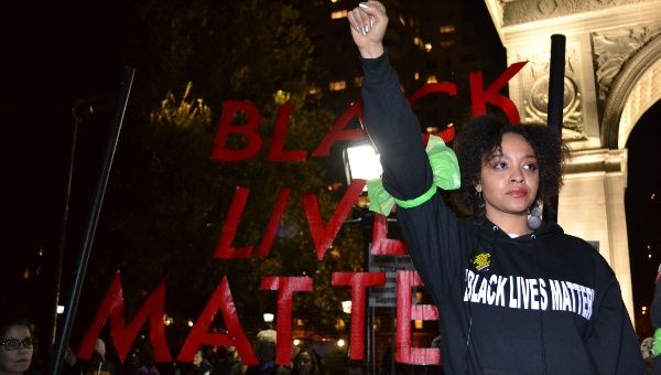 A protester holds up the power fist as she stands in front of a Black Lives Matter sign.