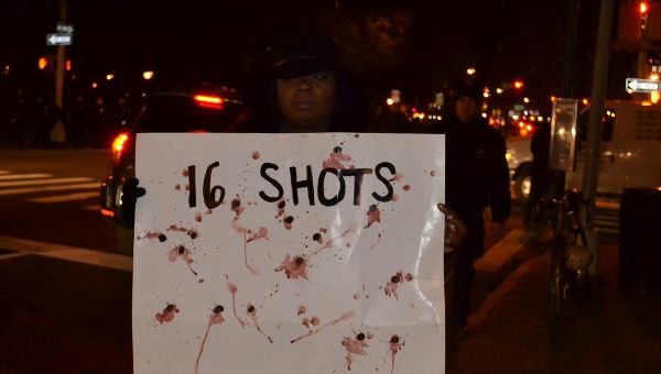 A protester holds a banner representing the 16 shots fired by police on unarmed teenager Laquan McDonald in Chicago. 