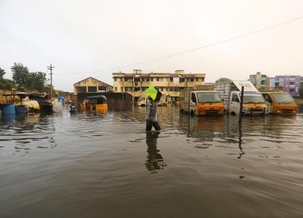 A man carries drinking water in a pitcher through a flooded street in Chennai, December 4, 2015.