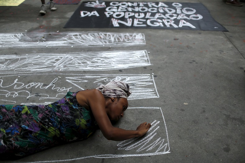 A woman draws pictures of coffins next to a sign condemning the murder of Black youth.