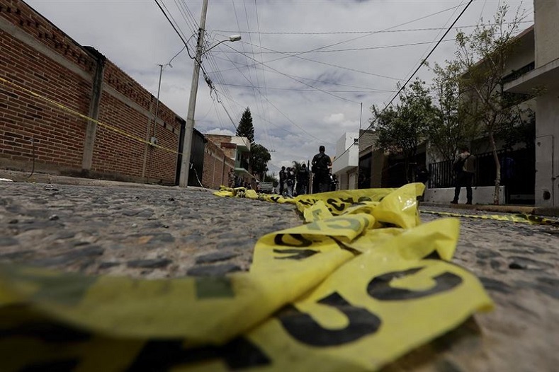 Yellow police tape lies on the road as federal agents work at a crime scene in Mexico.