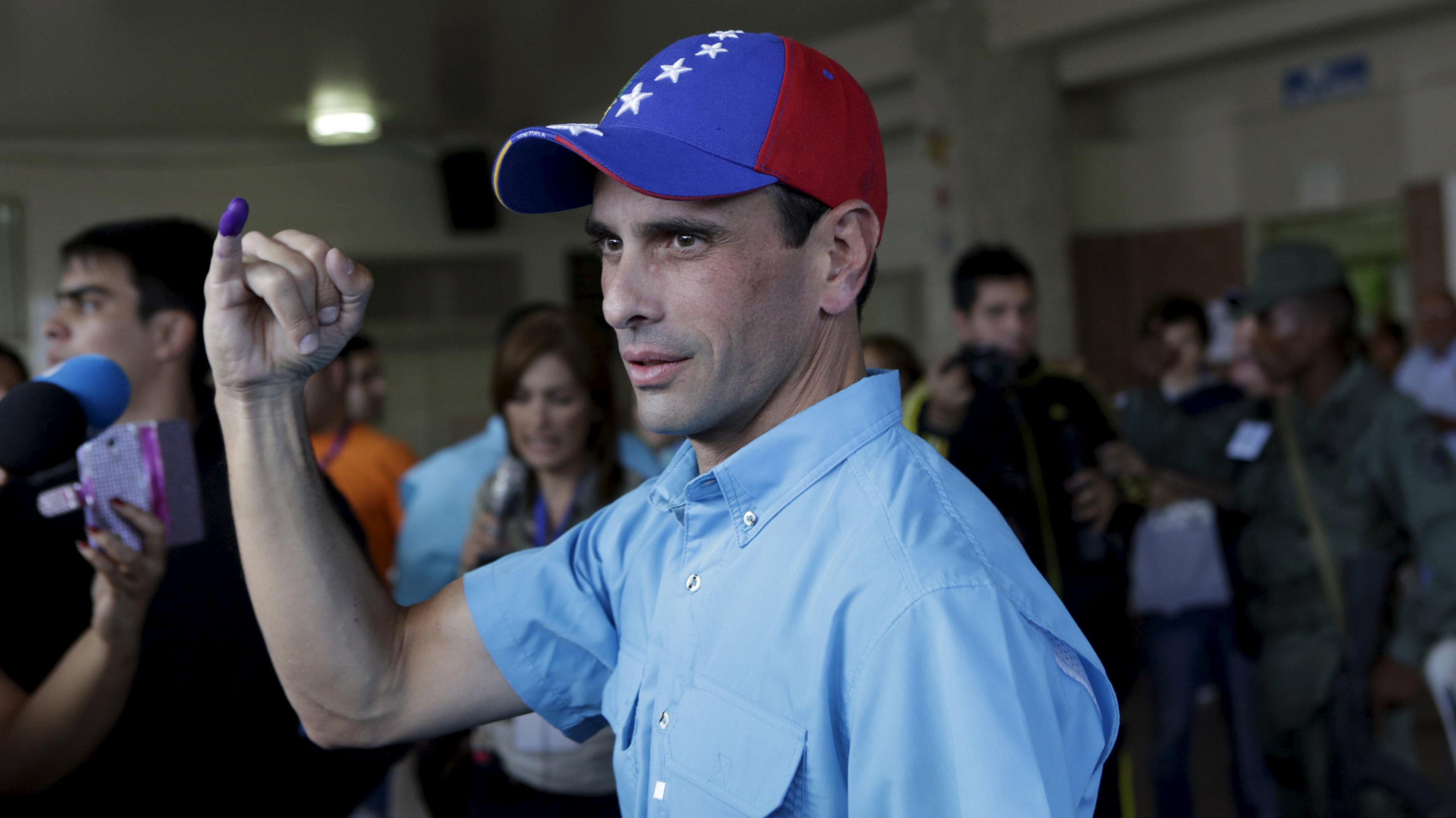 Venezuelan opposition leader Henrique Capriles shows his ink-stained finger after casting his vote at a polling station during a legislative election, in Caracas.
