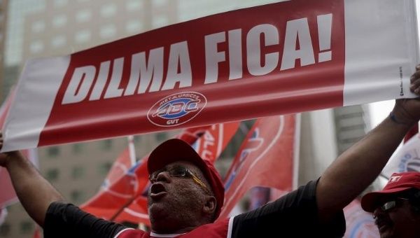A demonstrator holds a sign that reads “Dilma Stays” at a protest against the impeachment proceedings against President Dilma Rousseff, Brazil, Dec. 8, 2015.