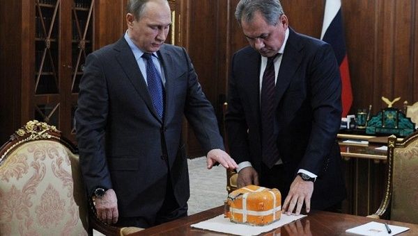 Russian President Vladimir Putin (L) and Defense Minister Sergei Shoigu examine the flight recorder from the Russian bomber shot down by a Turkish jet, Dec. 8, 2015.