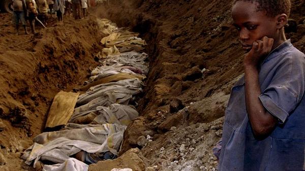A Rwandan refugee girl stares at a mass grave where dozens of bodies have been laid to rest outside Kigali in this July 20, 1994 file photo.