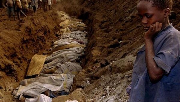 A Rwandan refugee girl stares at a mass grave where dozens of bodies have been laid to rest outside Kigali in this July 20, 1994 file photo. 