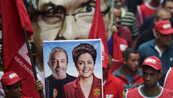 A banner of Brazil's former president Luiz Inacio Lula da Silva and President Dilma Rousseff appears in front of a banner displaying the head of the lower congressional house Eduardo Cunha during a pro-Dilma march on Dec. 8.