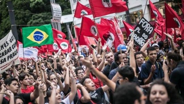 Demonstrators waving flags of the Landless Workers Movement march down the streets of Sao Paulo, Brazil, Dec. 16, 2015.