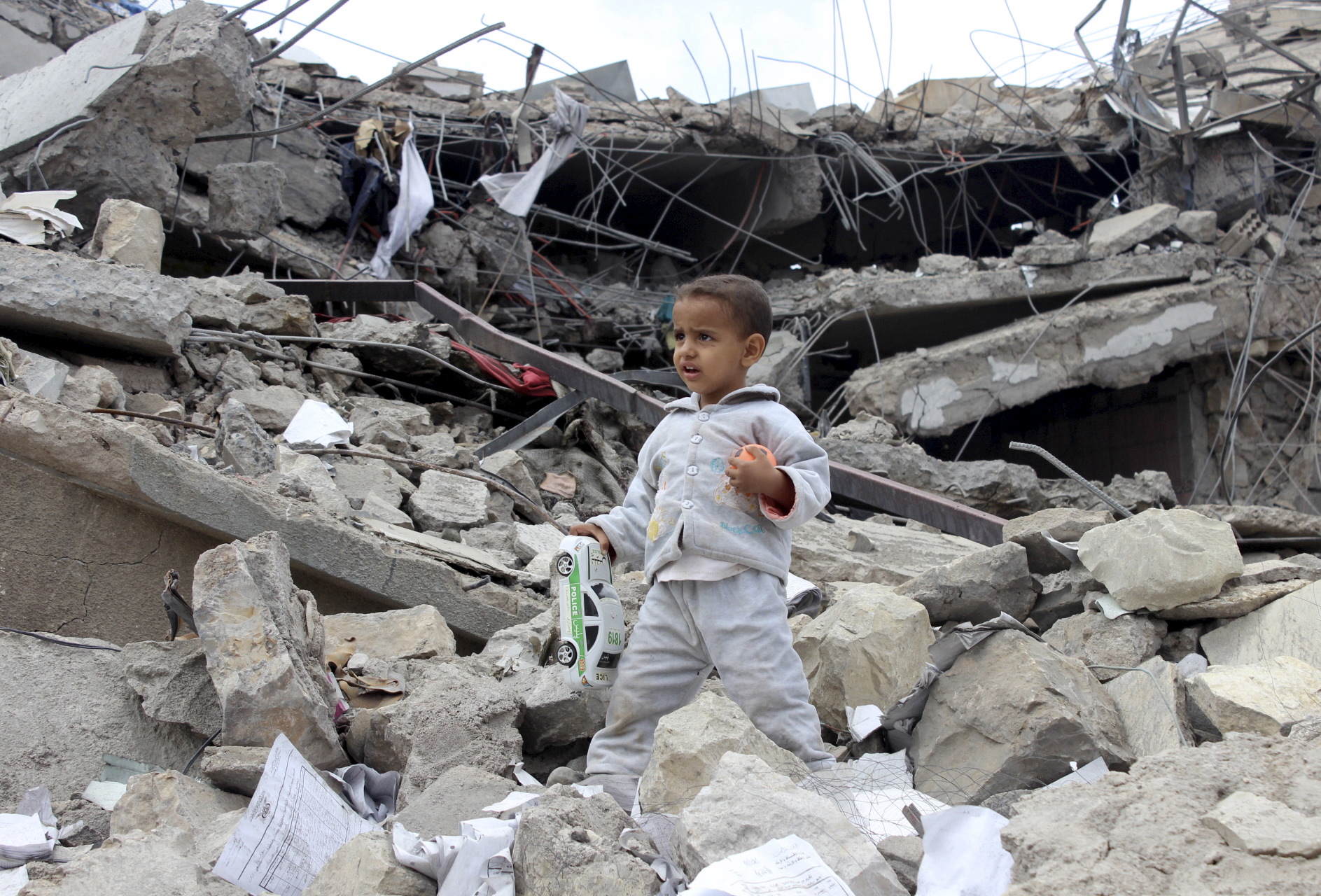 A boy collects toys in the rubble of a house destroyed by an airstrike in Yemen's northwestern city of Saada.