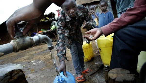 Children fill jerrycans with water they purchase from a private water vendor who manages the tap of the water kiosk in the Kibera slum in Nairobi, Kenya, 10 Dec. 2003. 