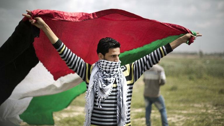 A protester waves a Palestinian flag towards the Israeli border fence between Israel and the Gaza Strip during a protest in 2014.