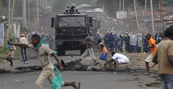 A protester runs past a Burundian police riot van in Musaga, on the outskirts of Bujumbura, on April 27, 2015.