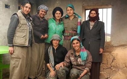 Kurdish Women fighters pose for a picture with a displaced Yazidi woman (R) who lives near the base in Sinjar.