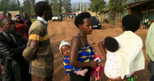 Mothers carrying their babies queue as they wait to cast their votes at a polling station in Rwanda's capital Kigali Dec. 18, 2015.