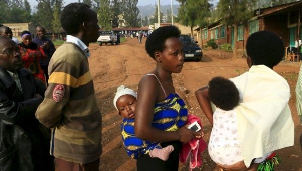 Mothers carrying their babies queue as they wait to cast their votes at a polling station in Rwanda's capital Kigali Dec. 18, 2015.