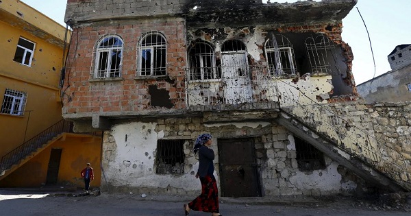 A woman walks past a building damaged during clashes between Turkish security forces and Kurdish militants, in the southeastern town of Silvan Turkey, Dec. 7, 2015.