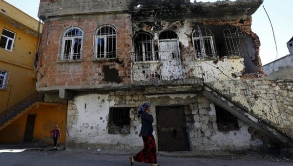 A woman walks past a building damaged during clashes between Turkish security forces and Kurdish militants, in the southeastern town of Silvan Turkey, Dec. 7, 2015.