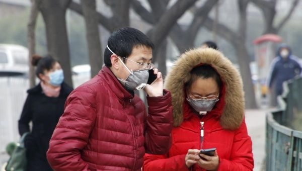 Pedestrians wearing protective masks are seen on a street on a heavily polluted day in Beijing, December 26, 2015.