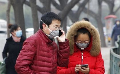 Pedestrians wearing protective masks are seen on a street on a heavily polluted day in Beijing, December 26, 2015.