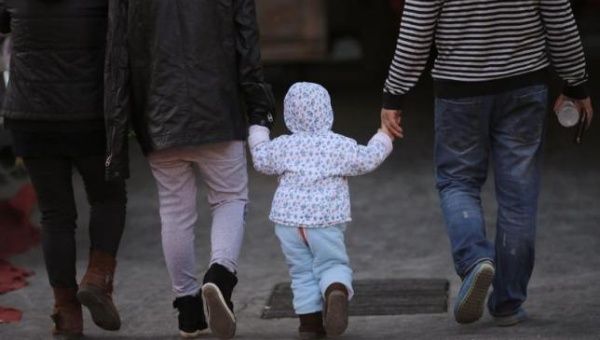 A girl holds the hands of her parents as they walk on a street in Beijing, Nov. 18, 2013