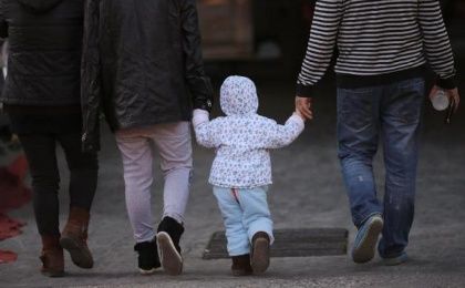 A girl holds the hands of her parents as they walk on a street in Beijing, Nov. 18, 2013