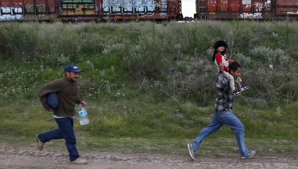 A Salvadoran father carries his son while running next to another immigrant as they try to board a train heading to the Mexican-U.S. border, in Huehuetoca, near of Mexico City, June 1, 2015.