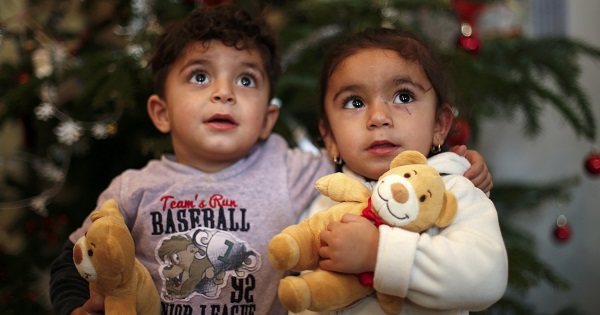 Two-year old twins Hevedar and Heve (R) of Iraq pose in front of a Christmas tree at a refugee shelter in Oberhausen, Germany, Dec. 22, 2015. Europe's refugee and migrant crisis has been one of the most important stories of the year and will surely mark generations of people to come.