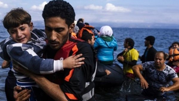 A man caries a child as they arrived with others refugees and migrants on a rubber boat on the Greek island of Lesbos after crossing the Aegean sea from Turkey.