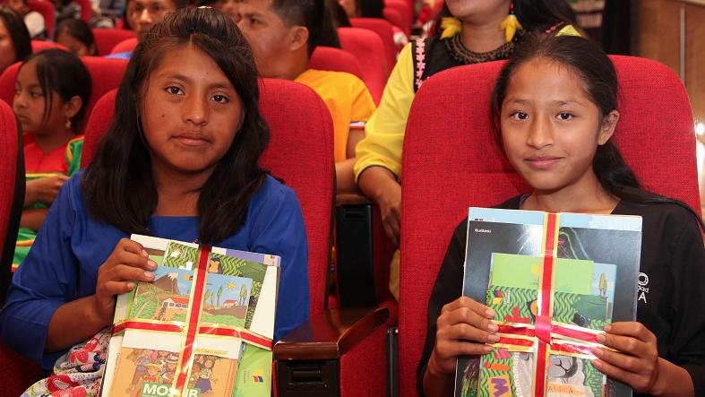 Two Ecuadorean children hold up a selection of material used in the country's Intercultural Bilingual Education System at a ceremonial event in Quito, Ecuador, Jan. 5, 2016.