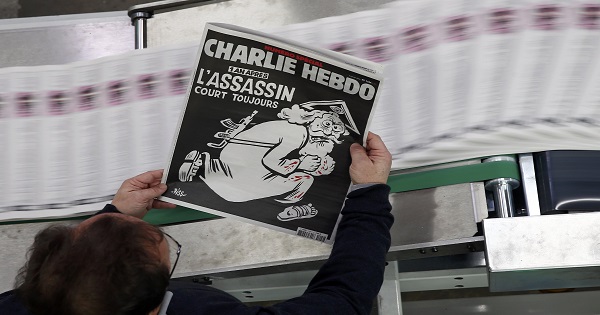 An employee of a printing house holds a copy of the latest edition of French weekly newspaper Charlie Hebdo with the title 